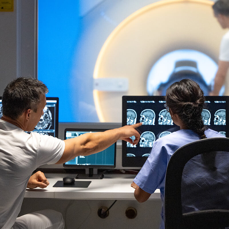Two MRI radiologists sitting in the control room and operating the MRI scanner